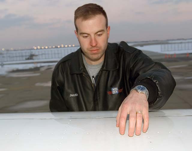 Pilot performing tactile inspection of wing