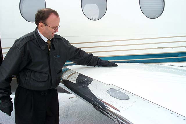 Pilot performing tactile check of aircraft wing