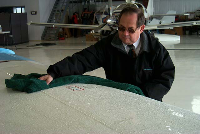 Pilot wiping moisture from aircraft in hangar